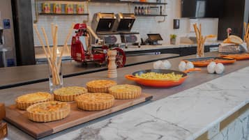 A kitchen counter with quiches, a grater, and a bowl of sliced vegetables.
