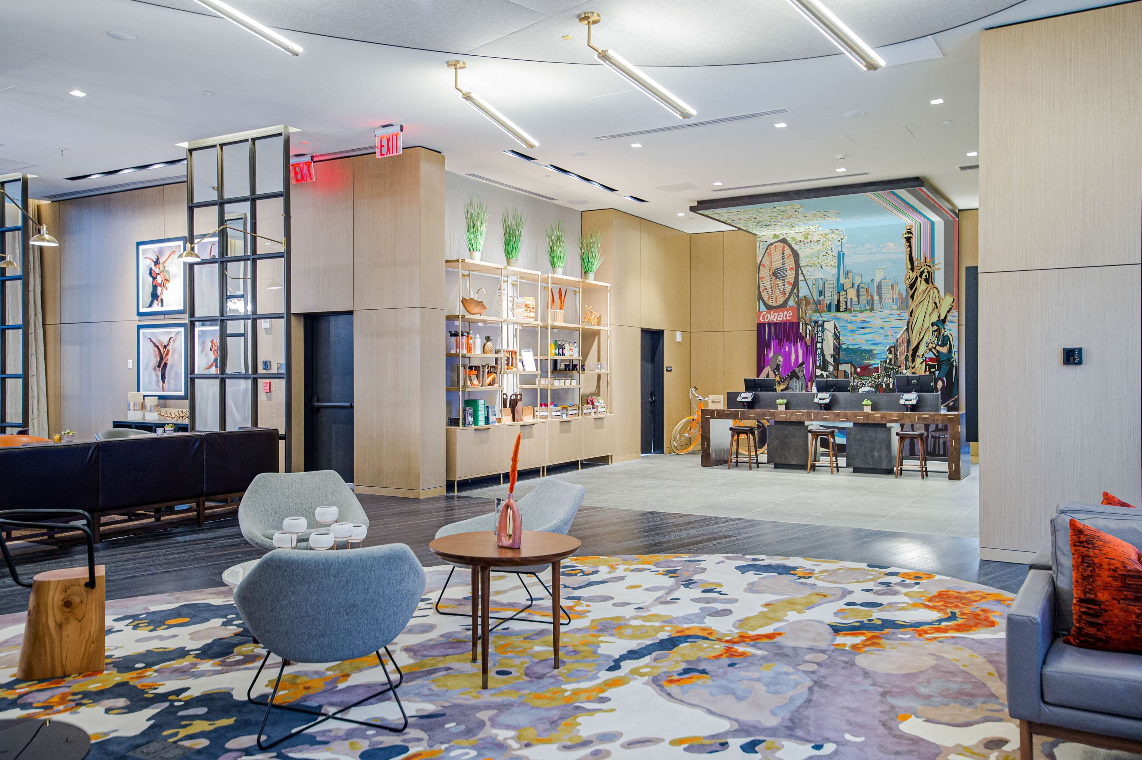 Een moderne lobby met een receptiebalie, zithoek en een muurschildering van de Vrijheidsbeeld.