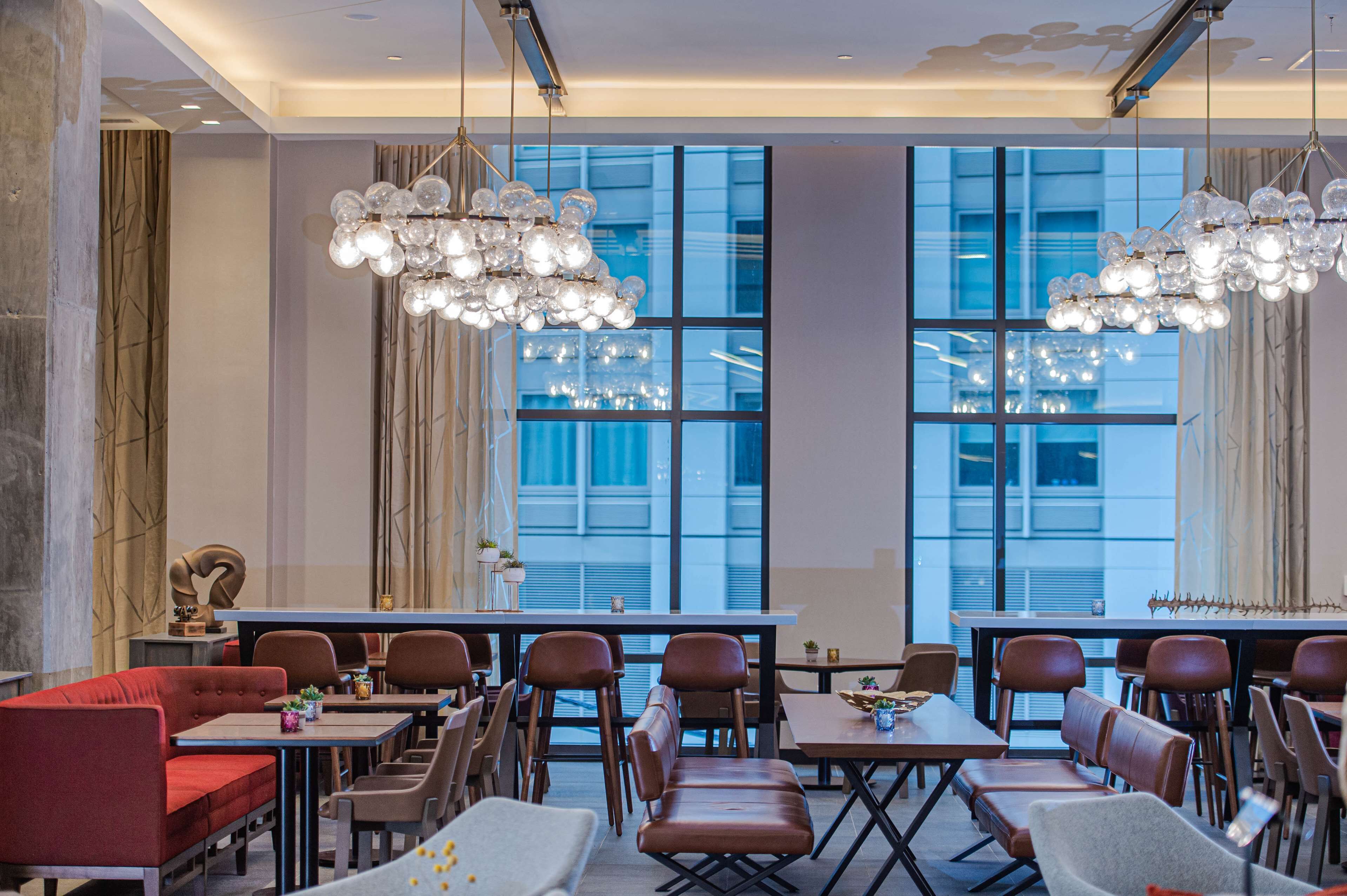 Un espace de restauration moderne, doté de hauts plafonds, de grandes fenêtres et d’un lustre.