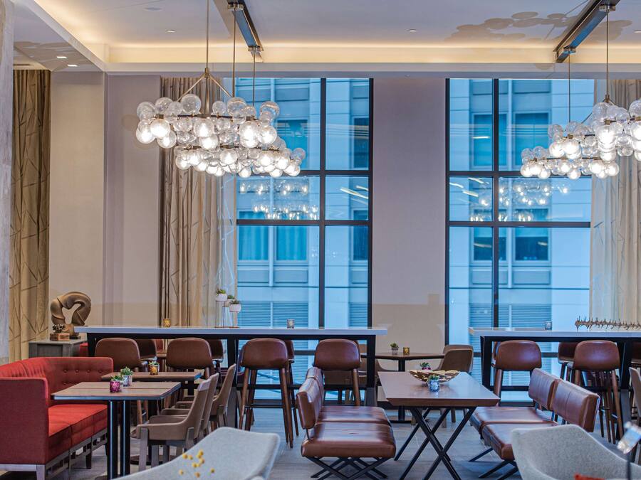 Un espace de restauration moderne, doté de hauts plafonds, de grandes fenêtres et d’un lustre.