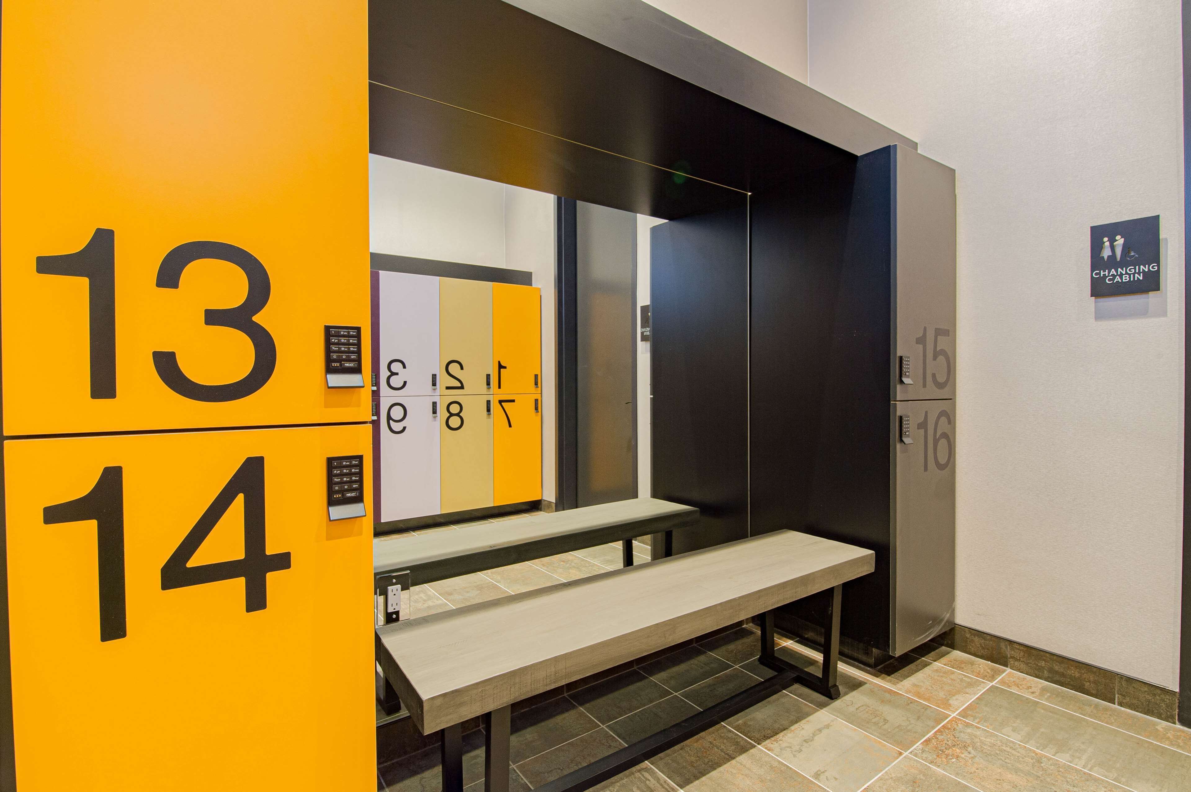 A modern elevator with numbered doors, a bench, and a changing cabin sign.
