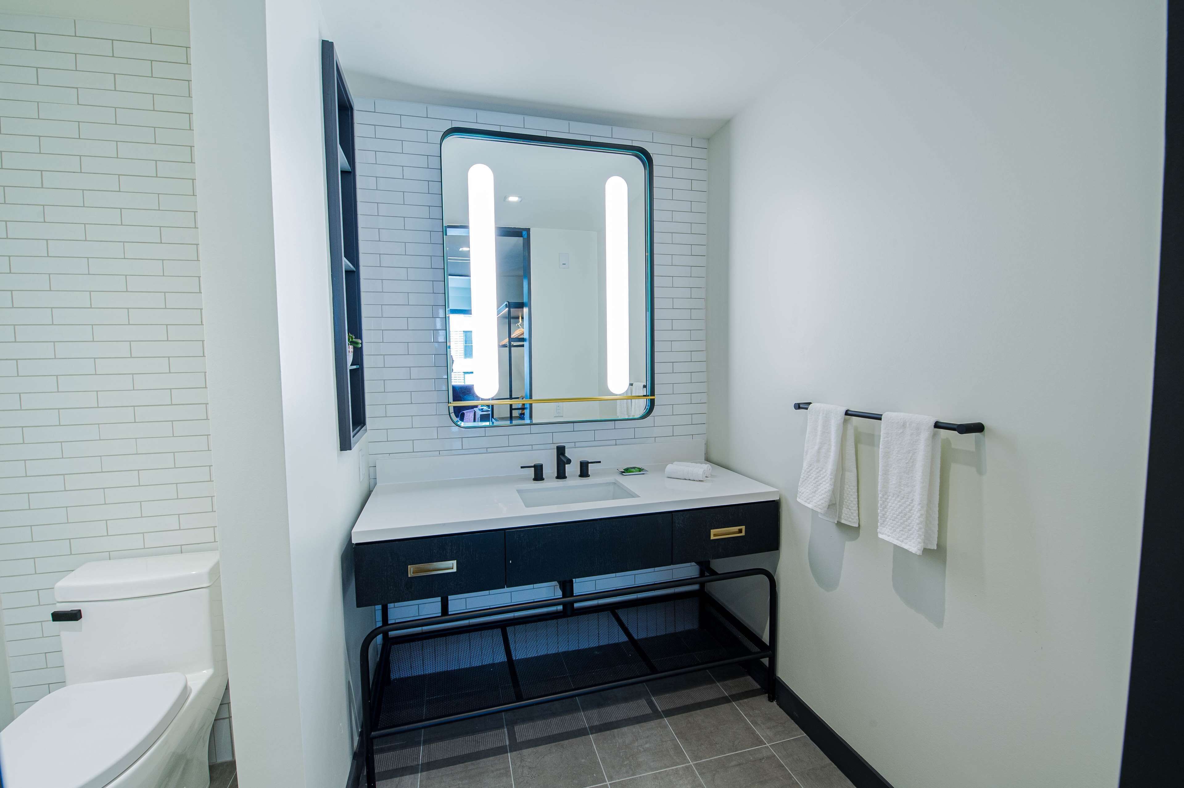 A bathroom with a white toilet, a sink with a mirror above it, and a towel rack with towels.