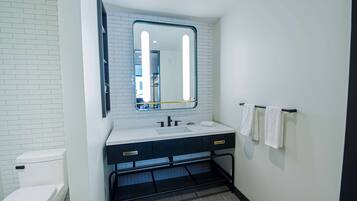 A bathroom with a white toilet, a sink with a mirror above it, and a towel rack with towels.