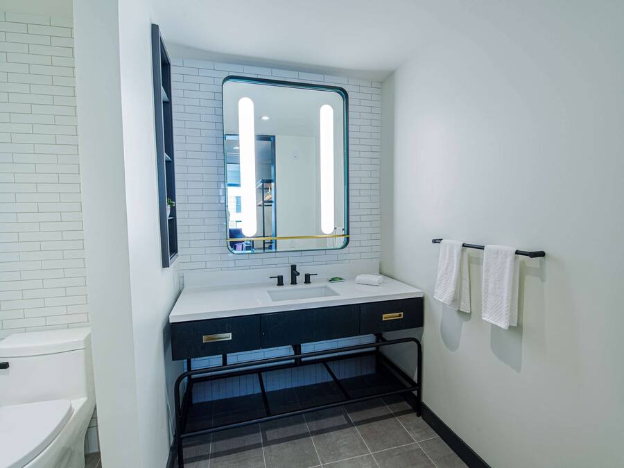 A bathroom with a white toilet, a sink with a mirror above it, and a towel rack with towels.