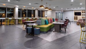 A modern lounge area with a green sofa, round tables, and yellow chairs. - Home2 Suites by Hilton Page Lake Powell (Page)