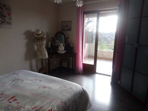 Une chambre à coucher avec un lit, une commode, un miroir et un balcon offrant une vue.