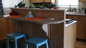 A kitchen with wooden cabinets, a ceiling fan, and a window with blinds.