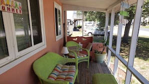 A porch with wicker furniture, including a sofa and chairs, and a small table.