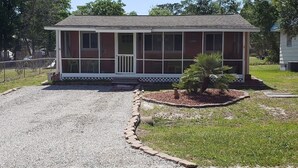 A single-story house with a front porch, a small garden, and a gravel driveway.