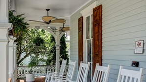 A porch with white rocking chairs, a ceiling fan, and a sign reading "Main House". - The Ashley Rose (Cape May)