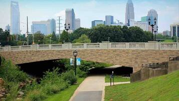 A cityscape with a stone bridge, a pedestrian path, and a grassy area.