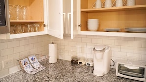 A kitchen with granite countertops, a coffee maker, a toaster, and open cabinets with glassware and dishes. - Modern Cozy 1BR ◉ Gym ◉ Balcony ◉ Free Parking (Charlotte)