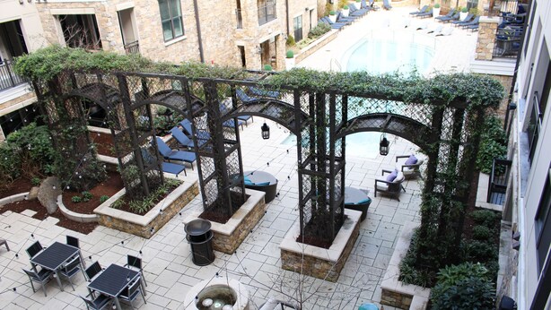 A rooftop patio with outdoor seating, a swimming pool, and a stone building in the background. - Modern Cozy 1BR ◉ Gym ◉ Balcony ◉ Free Parking (Charlotte)