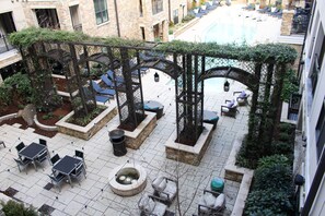 A rooftop patio with outdoor seating, a swimming pool, and a stone building in the background. - Modern Cozy 1BR ◉ Gym ◉ Balcony ◉ Free Parking (Charlotte)