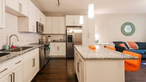A modern kitchen with white cabinetry, stainless steel appliances, and a granite countertop. - Modern Cozy 1BR ◉ Gym ◉ Balcony ◉ Free Parking (Charlotte)