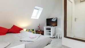 Ein Schlafzimmer mit einem Bett, einem Fernseher, einem kleinen Tisch und einem Fenster.
