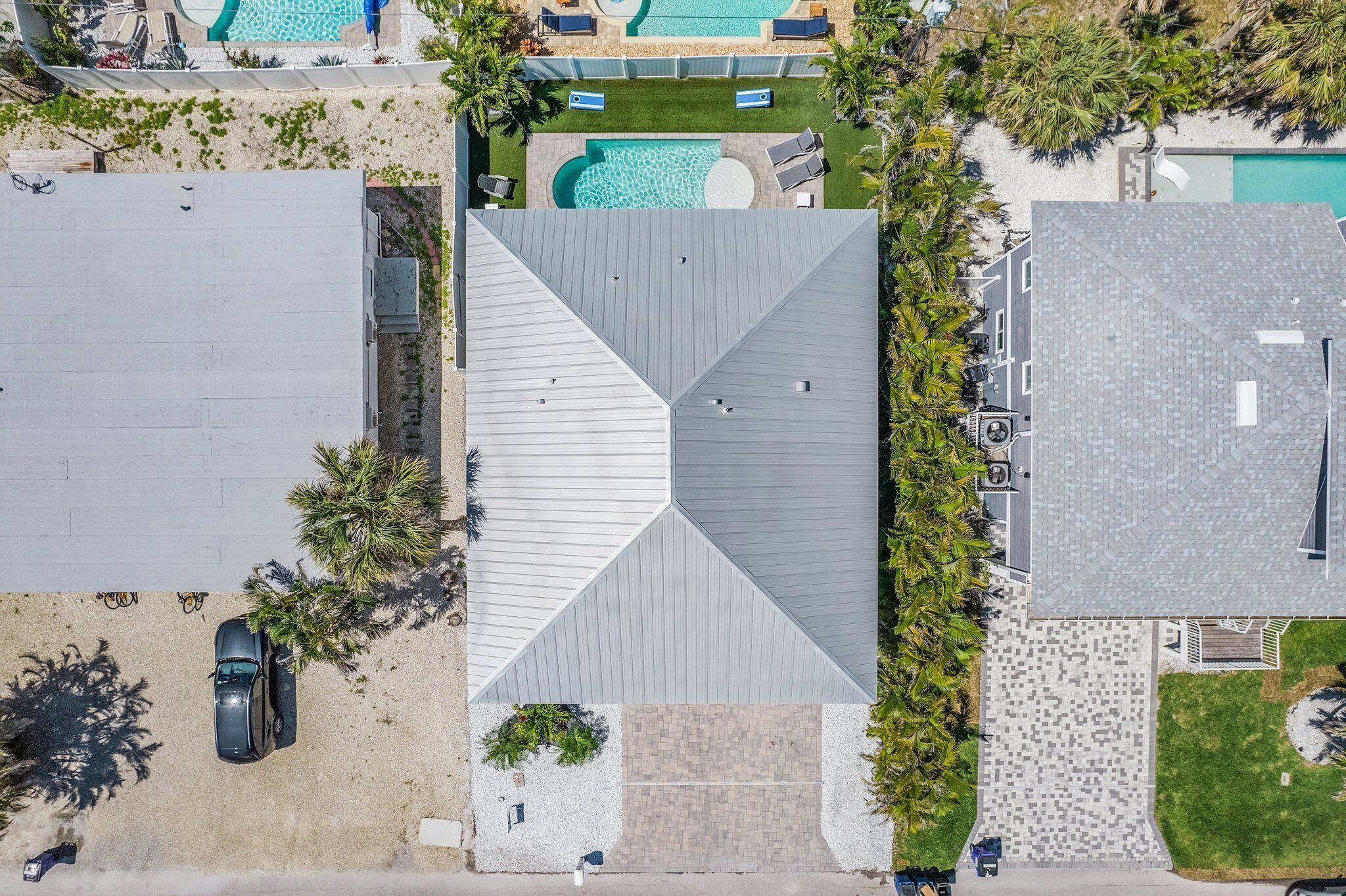 Eine Übersichtsansicht eines Anwesens mit großem Schwimmbad, überdachter Terrasse und Parkplatz.