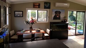 Ein Essbereich mit einem Klavier, einem Aquarium und Blick ins Freie durch eine Schiebetür.