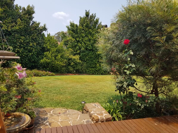 A well-maintained garden with a stone pathway leading to a wooden deck. - Relax and Enjoy a little bit of Sanctuary in Jervis Bay (Sanctuary Point)