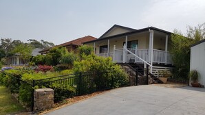 Ein Wohnhaus mit Veranda, einer Treppe zum zweiten Stock und einer Auffahrt.