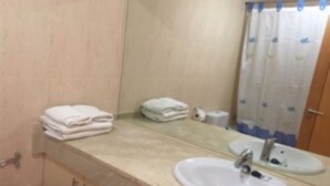 A bathroom with a sink, mirror, and towel stack.