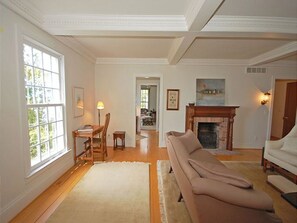 A spacious living room with a beige sofa, a fireplace, and a large window.