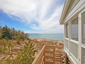 A wooden deck with a view of the ocean and a building with white trim and large windows.