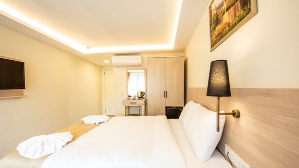Una habitación de hotel con cama, mesita de noche, lámpara y un cuadro en la pared.