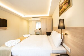 Een hotelkamer met een bed, nachtkastje, lamp en een schilderij aan de muur.