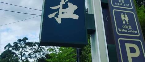 A signpost with multiple directional arrows and icons indicating amenities such as a hostel, local food, and a water closet.
