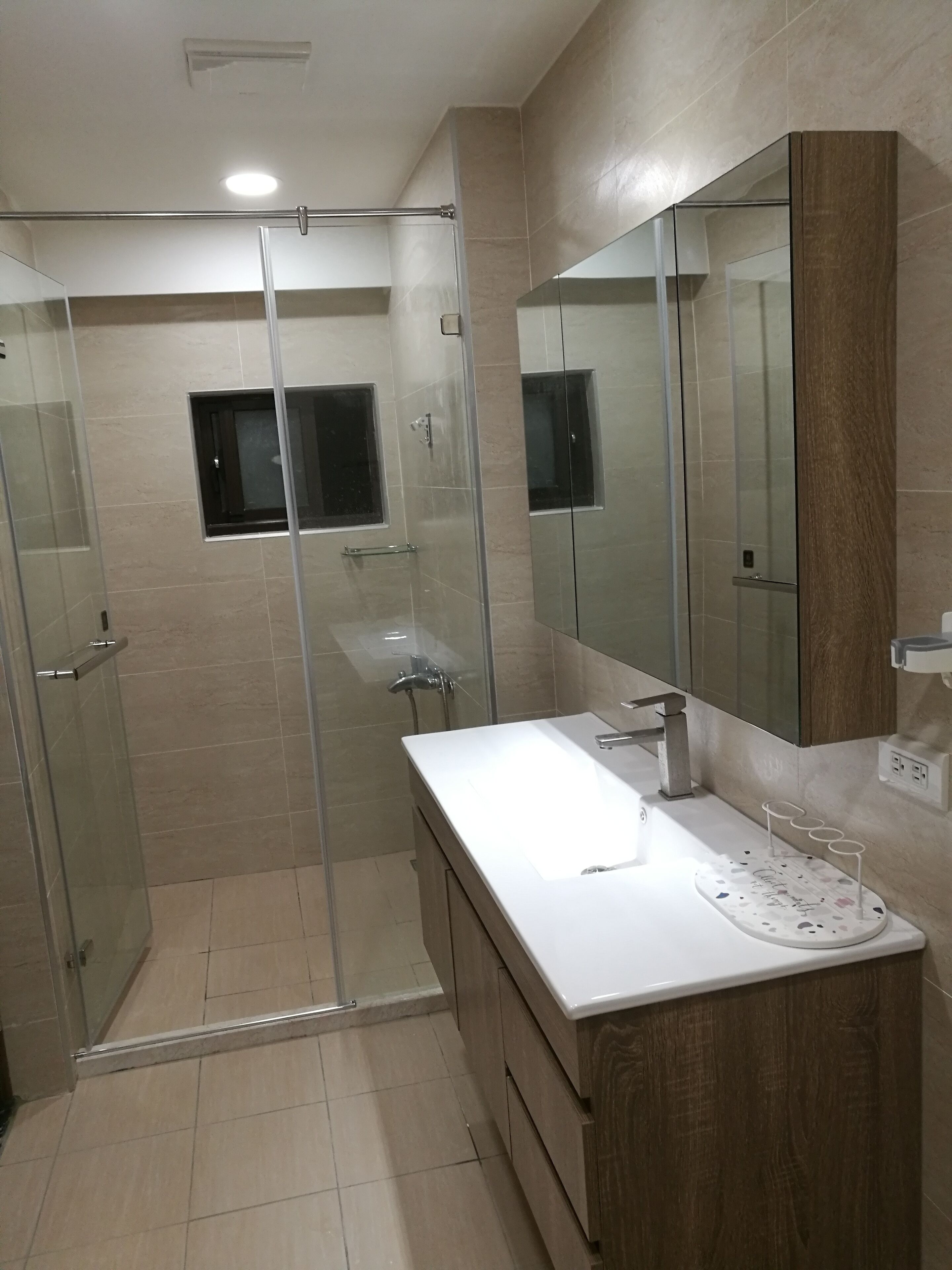 Une salle de bain moderne avec une douche à parois de verre, un lavabo blanc et un grand miroir.
