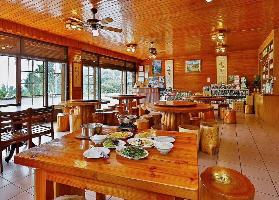 A restaurant with wooden interiors, multiple dining tables, and a variety of dishes displayed.