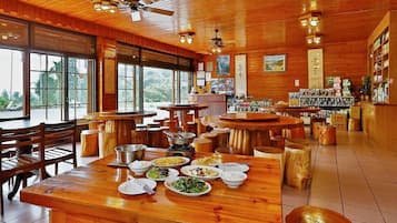 A restaurant with wooden interiors, multiple dining tables, and a variety of dishes displayed.