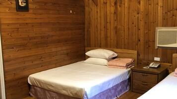 Un dormitorio de cabaña de madera con dos camas, una mesita de noche con un teléfono y un cuadro en la pared.