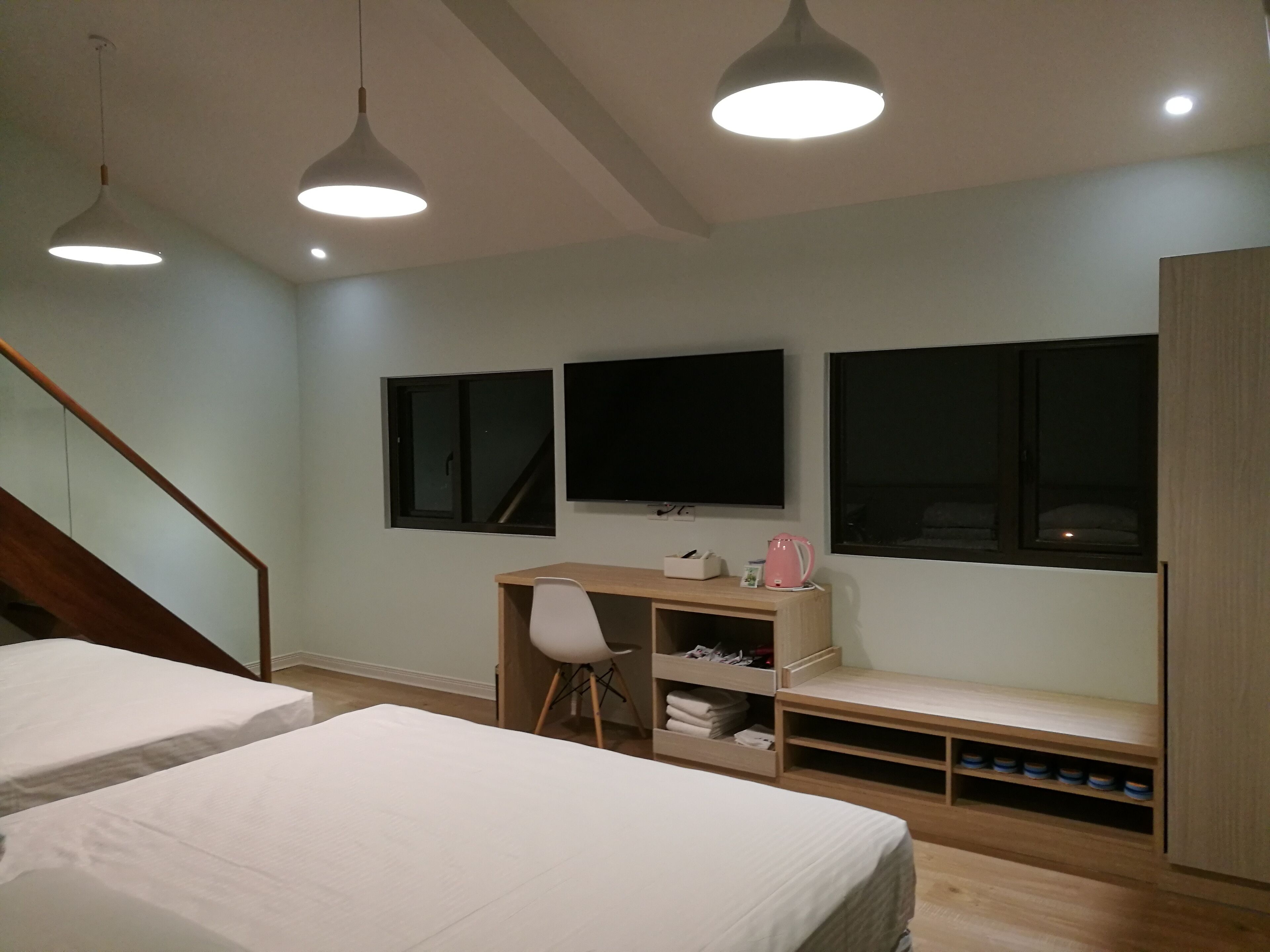 A bedroom with two beds, a desk, a chair, and a TV.