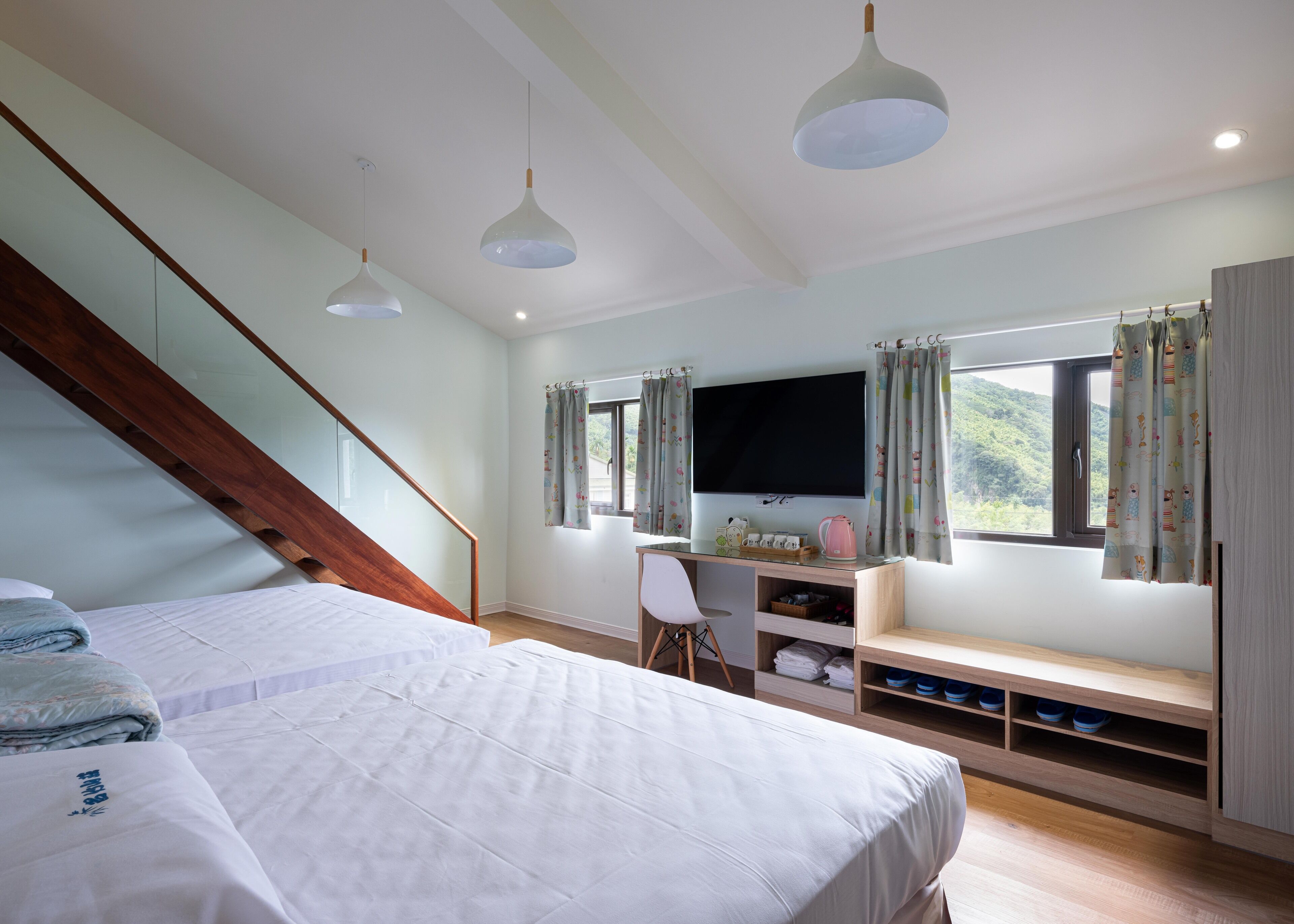 A bedroom with a bed, a desk, a chair, a TV, and a window with curtains.