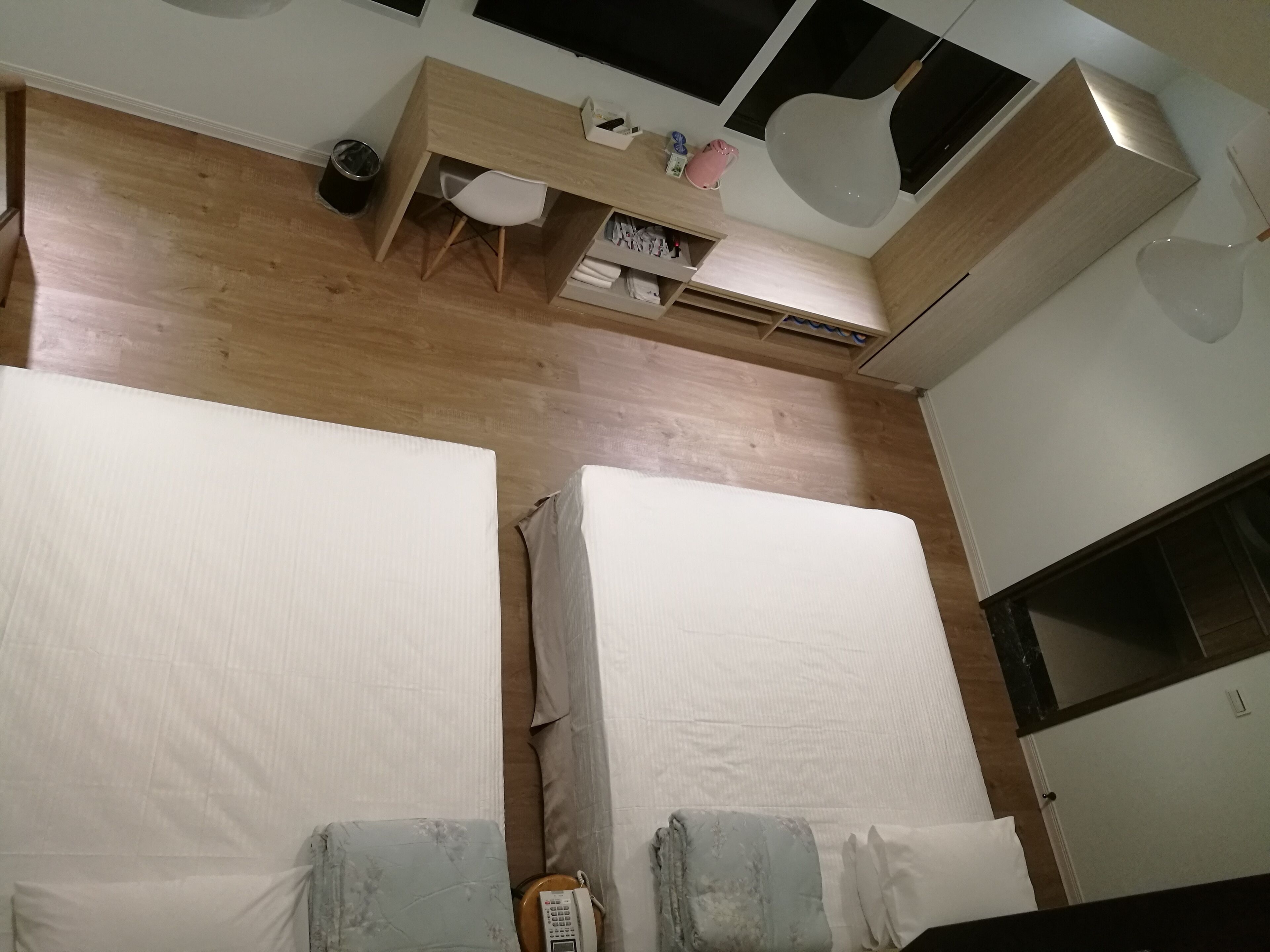 A bedroom with two beds, a desk, and a wardrobe.
