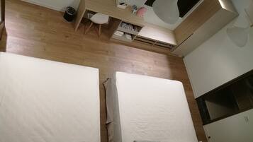 A bedroom with two beds, a desk, and a wardrobe.