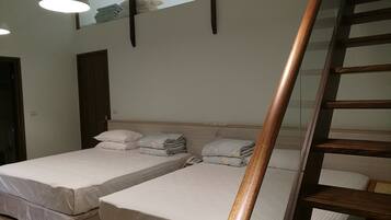A hotel room with two beds, a wooden staircase, and a ceiling light fixture.