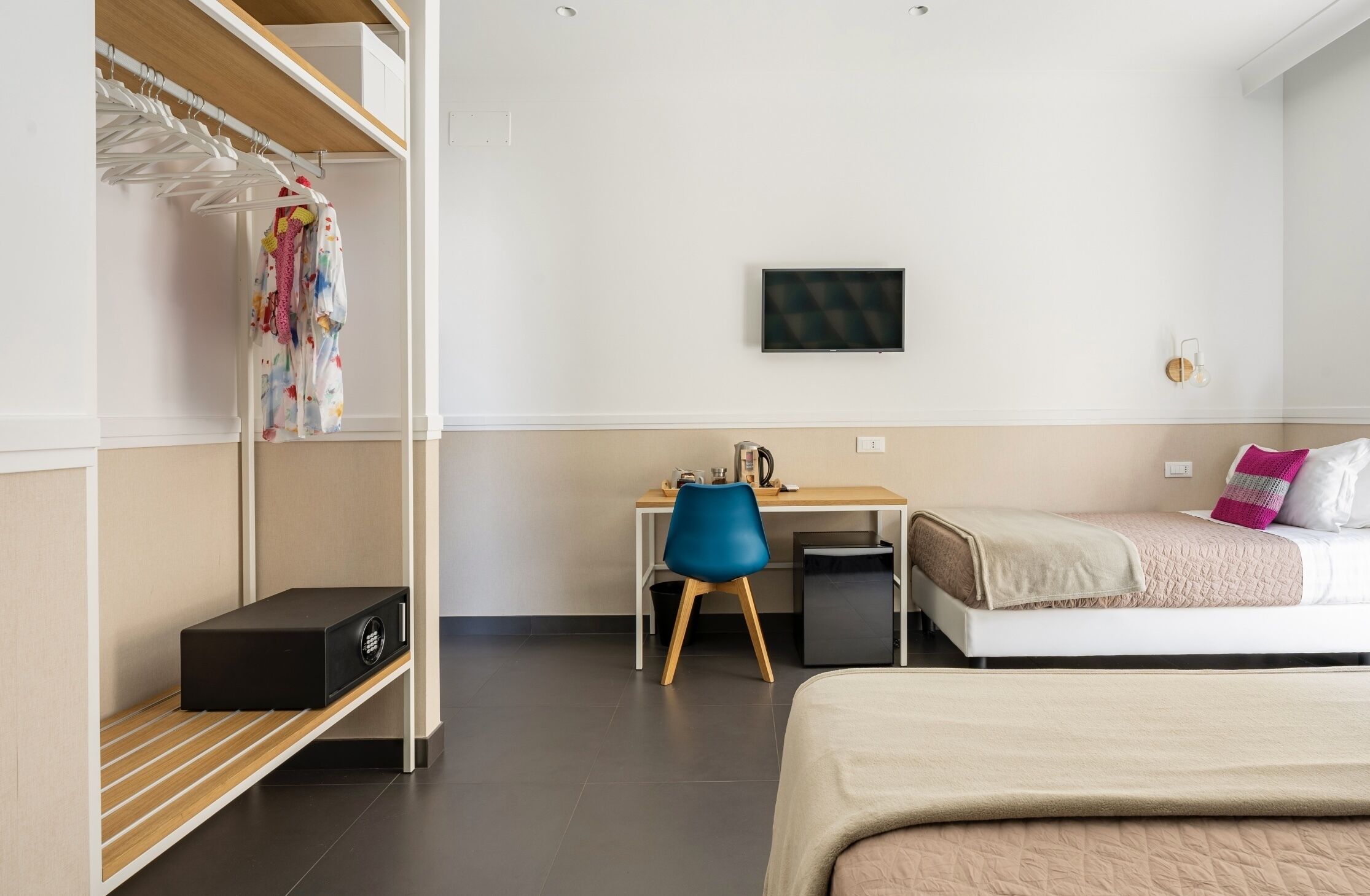 A bedroom with a bed, a desk, a chair, a TV, and a wardrobe.