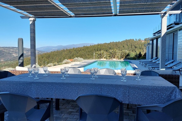 Área da piscina com churrasqueira, área de refeições e lazer.