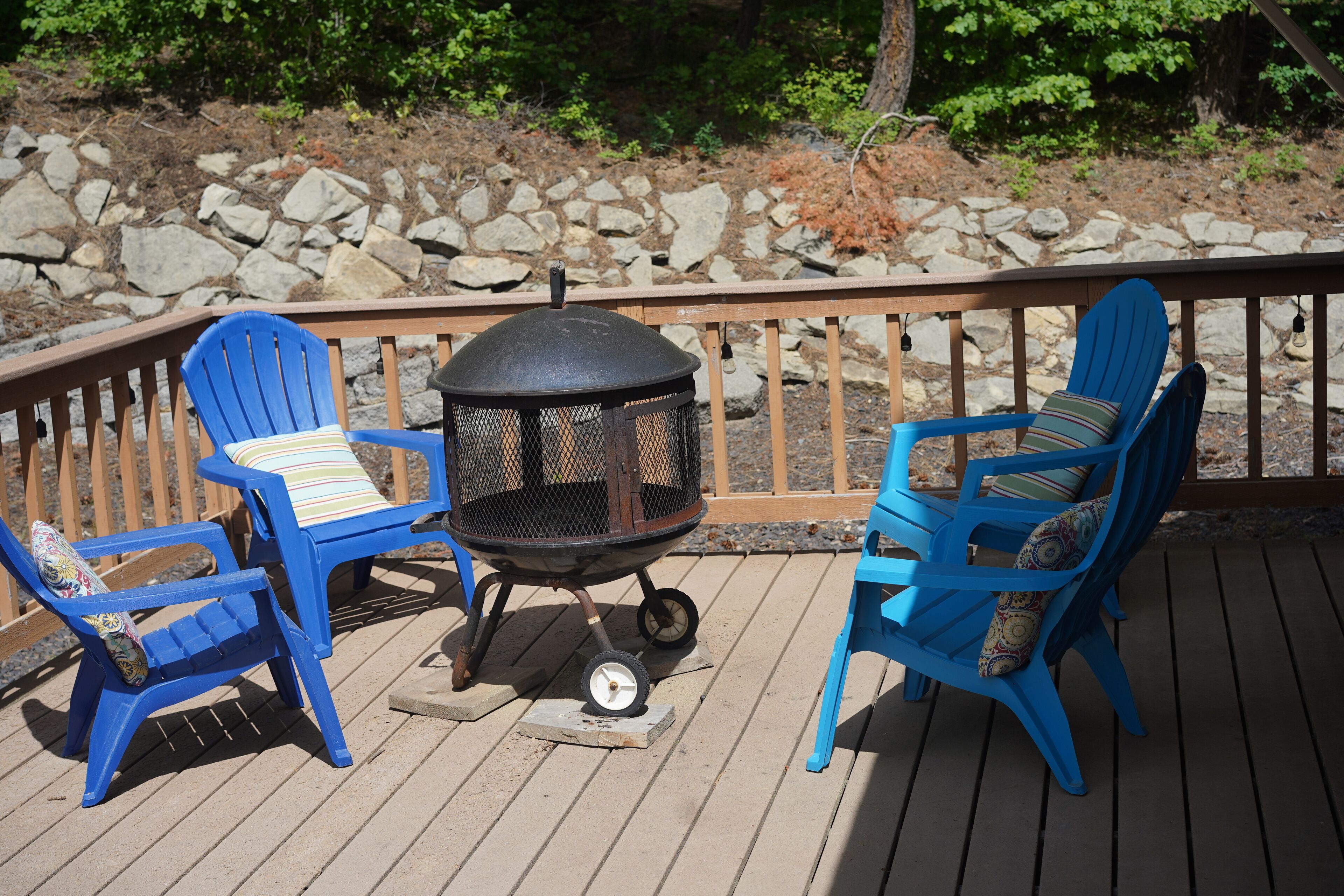 Une terrasse avec deux chaises Adirondack bleues et un barbecue noir.