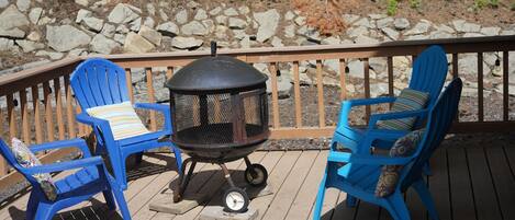 Une terrasse avec deux chaises Adirondack bleues et un barbecue noir.