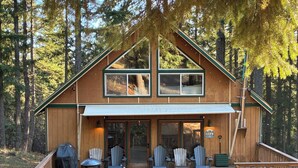 A cabin with a porch, outdoor seating, and a sign reading "Welcome Cabin".