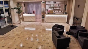 A hotel lobby with a reception desk, seating area, and a bar. - Hotel Cristoforo Colombo (Cesenatico)