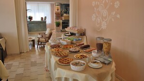 A buffet table with various baked goods and beverages, set in a room with a floral wall design and a view of a balcony. - Hotel Cristoforo Colombo (Cesenatico)