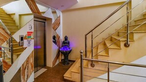 A modern hotel interior with a staircase, elevator, and a statue with a blue light. - Aira Xing (New Delhi)