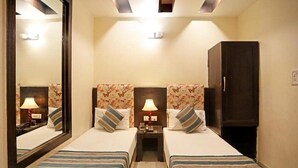 A hotel room with two beds, a large mirror, a wardrobe, and a nightstand with lamps. - Aira Xing (New Delhi)