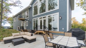 Una casa moderna con un patio que tiene un sofá modular, una mesa de comedor con sillas y una parrilla.