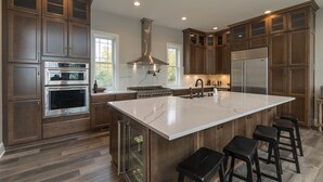 Una cocina moderna con una isla grande, electrodomésticos de acero inoxidable y armarios de madera.